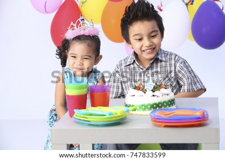 Boy with in front of  birthday cake with sister