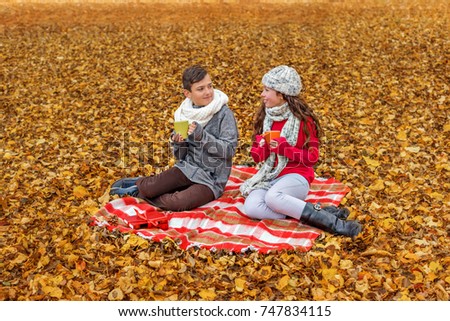 adorable teens communicate drink tea talk while sitting in a park on a plaid picnic