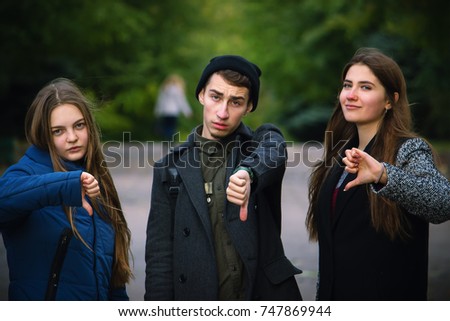Group of young boy and two girls showing thumb down in the street park