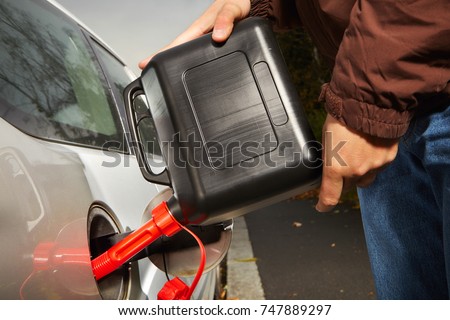 Detail of man with plastic canister filling car tank on street
