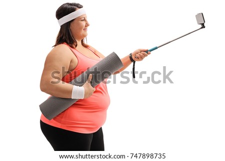Overweight woman holding an exercise mat and taking a selfie with a stick isolated on white background