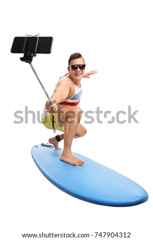 Young man surfing and taking a selfie with a stick isolated on white background
