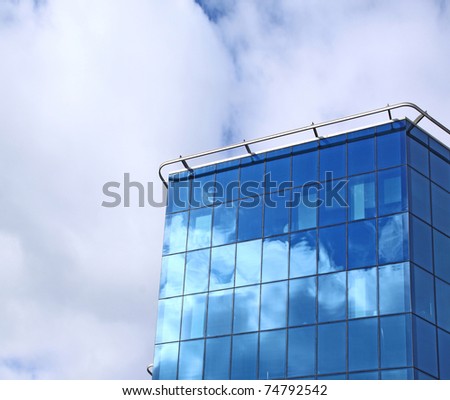 Modern office house from dark blue glass on a background sky