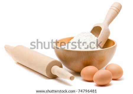 Baking ingredients - flour in bowl with eggs and rolling pin over white background Royalty-Free Stock Photo #74796481