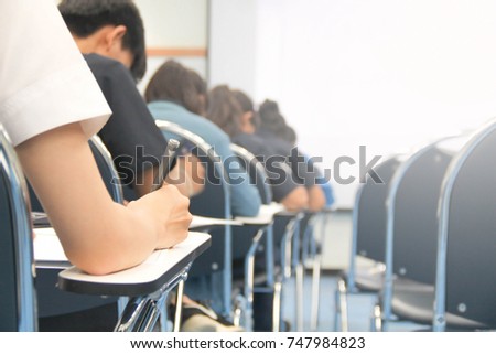 Hands university student holding pen writing /calculator doing examination / study or quiz, test from teacher or in large lecture room, students in uniform attending exam classroom educational school. Royalty-Free Stock Photo #747984823