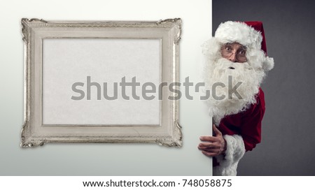Santa Claus peeking behind a wall and blank decorative frame, Christmas and holidays concept