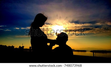 Silhouette of happy romantic couple at the beach, Man kisses woman's hand