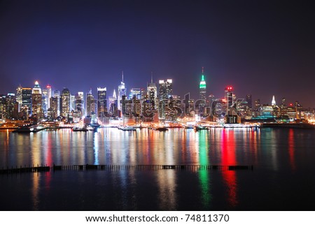 New York City Skyline at night with Times Square and Empire State Building with colorful reflections.