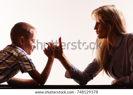 Spending time with family fun and family bonds. Mother and son arm wrestle and have fun indoors.