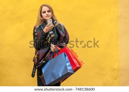 Modern teenager stand outside with bags and dialing mobile phone