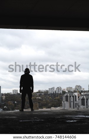 Silhouette of Homeless guy on Abandoned building with city on background