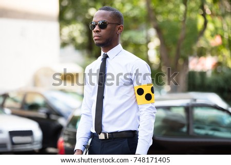 Portrait Of Blind Man Wearing Yellow Arm Band And Sunglasses Standing Outdoors