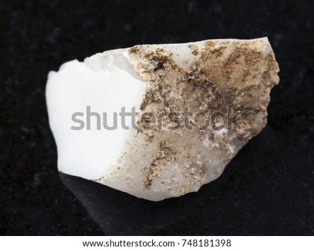 macro shooting of natural mineral rock specimen - raw cacholong (white opal) stone on dark granite background from Kazakhstan
