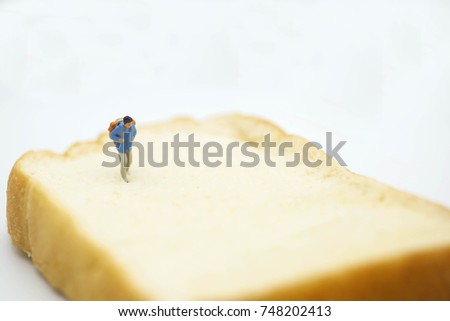 Miniature people: Traveler figure toy with bread using as background travel and food concept.