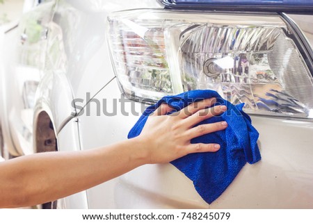 Worker cleaning car with blue microfiber cloth.