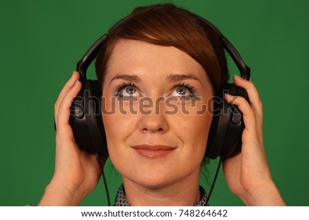 Beautiful young girl with black headphones on a green background.