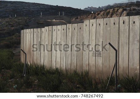 A section of the concrete Israeli West Bank barrier wall, with the world "Palestine" written on it, viewed from West Bank, Palestine Royalty-Free Stock Photo #748267492