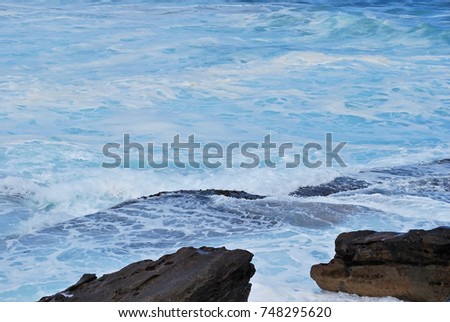 Porous rock and lots of sea foam in azure water at Bondi Beach