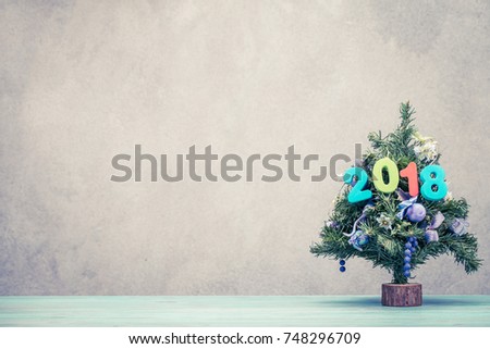 New Year tree with 2018 date on wooden table front old vintage concrete wall background. Holiday greeting card concept. Retro old style filtered photo