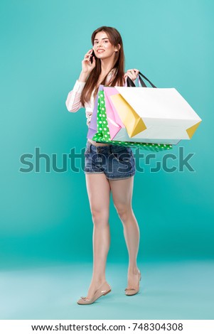 beautiful happy woman with shopping bags and phone on blue background.