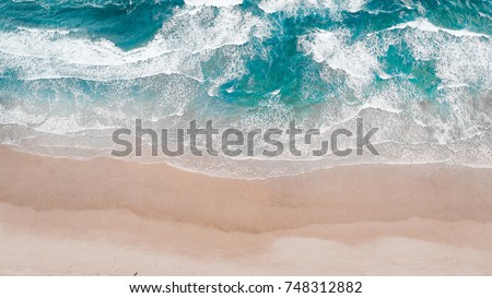 Surfing Aerial, Beach on aerial drone top view with ocean waves reaching shore, top view aerial photo from flying drone of an amazingly beautiful sea landscape. Royalty-Free Stock Photo #748312882