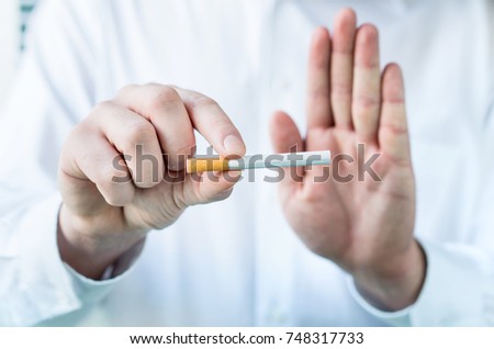 Doctor telling to quit smoking. Holding cigarette between fingers and showing stop sign with hand.