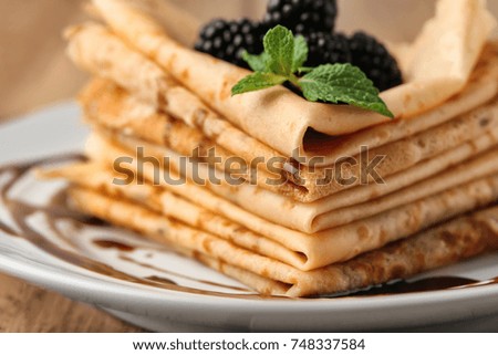 Delicious thin pancakes and berries on plate, closeup