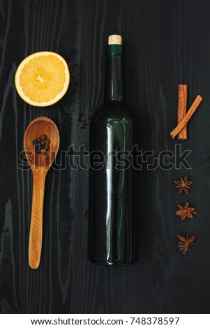 Set of ingredients for hot wine, orange, cinnamon, anise, bottle of wine, wooden spoon and  on the black wooden background