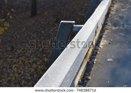 metallic handrail of pedestrian bridge covered by white frost