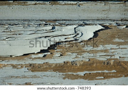 Flaking gray paint on a wood surface.