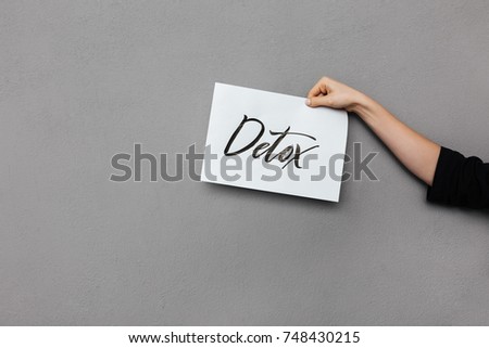 Close up photo of woman hand holding postcard on gray background