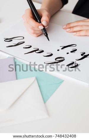 Close up photo of young woman hands writing alphabet on paper on desk  isolated