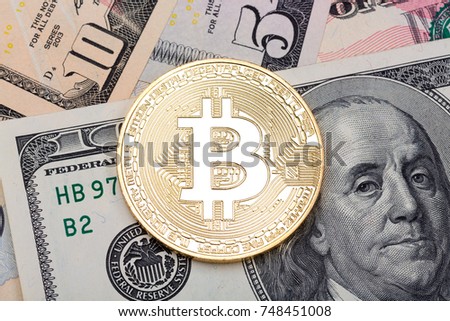 Close up of golden bitcoin on US dollars background. High resolution photo.