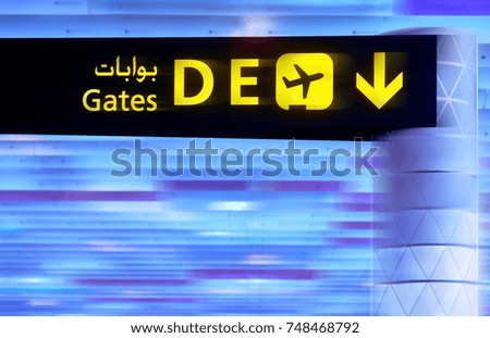 A blur picture of English-arabian yellow illuminated sign at airport with gate letters for departing flights. For background use.