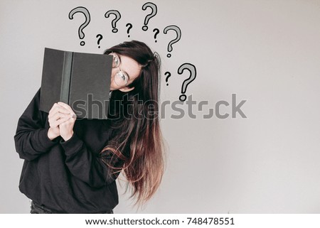 Young asian Student woman holding book and question marks doodles at the back ground with copy space