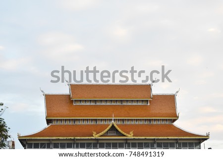 The orange tile roof of the Thai building on the sky background. 