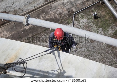 Top view male worker rope access  inspection of plumpness storage tank industry below pipeline oil
