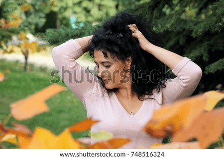 Autumn scene with a woman in the park and lots of yellow leaves