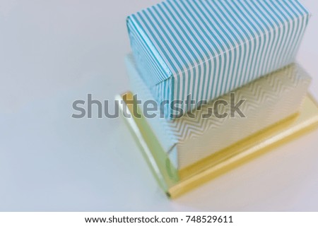 Horizontal picture of three stacked present boxes with modern minimalist packaging.