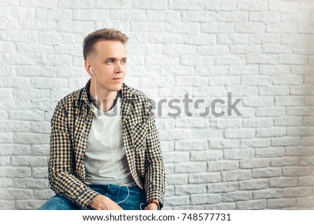 Man Sitting Listening Music Earphones Concept agains wall