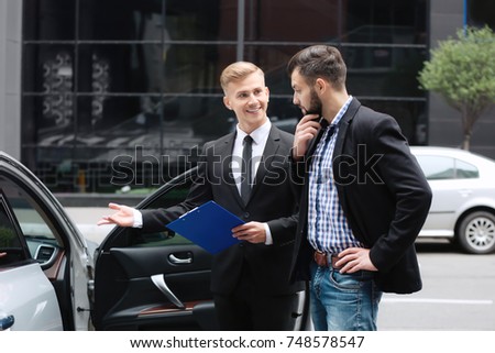 Young man with car dealer outdoors