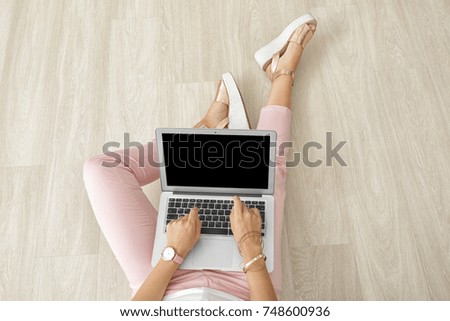 Young beautiful woman using laptop while sitting on floor