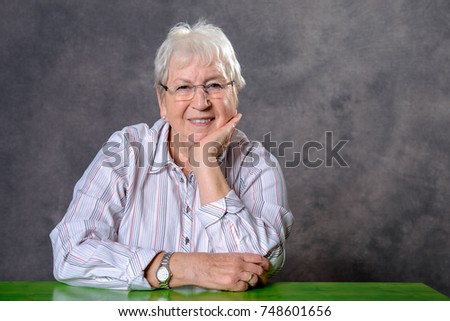 gray hairy elderly woman with glasses looking relaxed