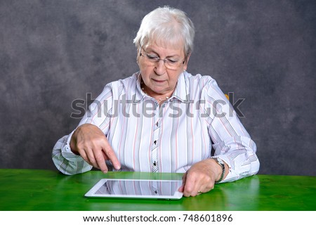 gray hairy elderly woman using tablet pc and smiling