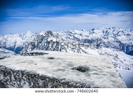 A stone tabletop with space for your product or advertising text. View of winter alpine mountains. Beautiful December sky in blue color.