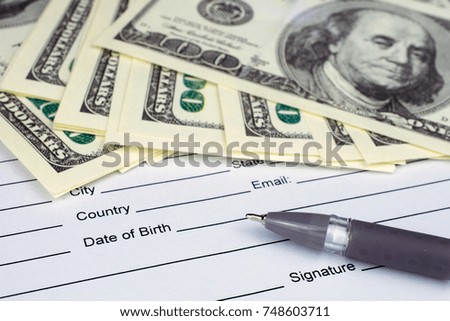 pen laying over a contract waiting to be signed money dollars