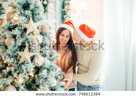 Cute, young couple decorating a Christmas tree.