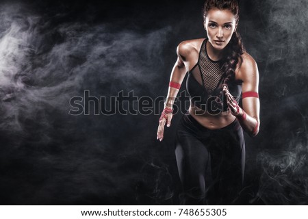 A strong athletic, woman sprinter, running on black background wearing in the sportswear, fitness and sport motivation. Runner concept with copy space. Royalty-Free Stock Photo #748655305