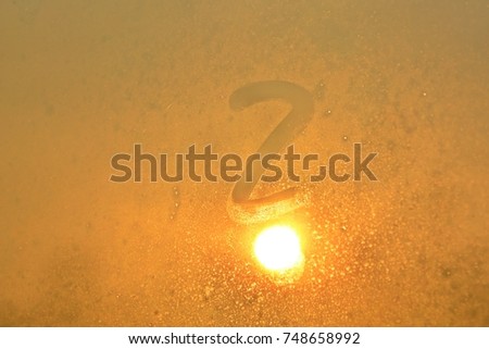 Question mark on a fogged window in the sunset