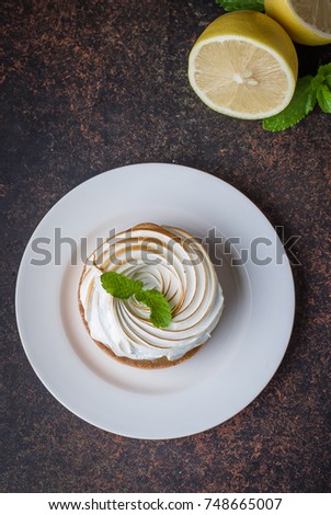 Delicious Lemon tart tartlet with meringue and mint on dark stone concrete table background. Copy space, top view